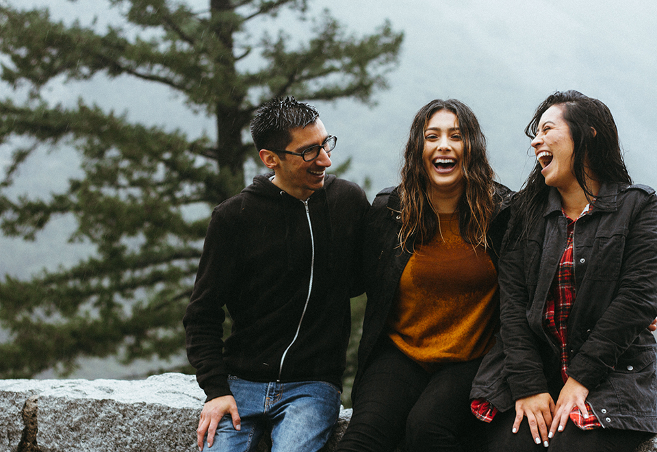 Three people seated outside, and they are laughing