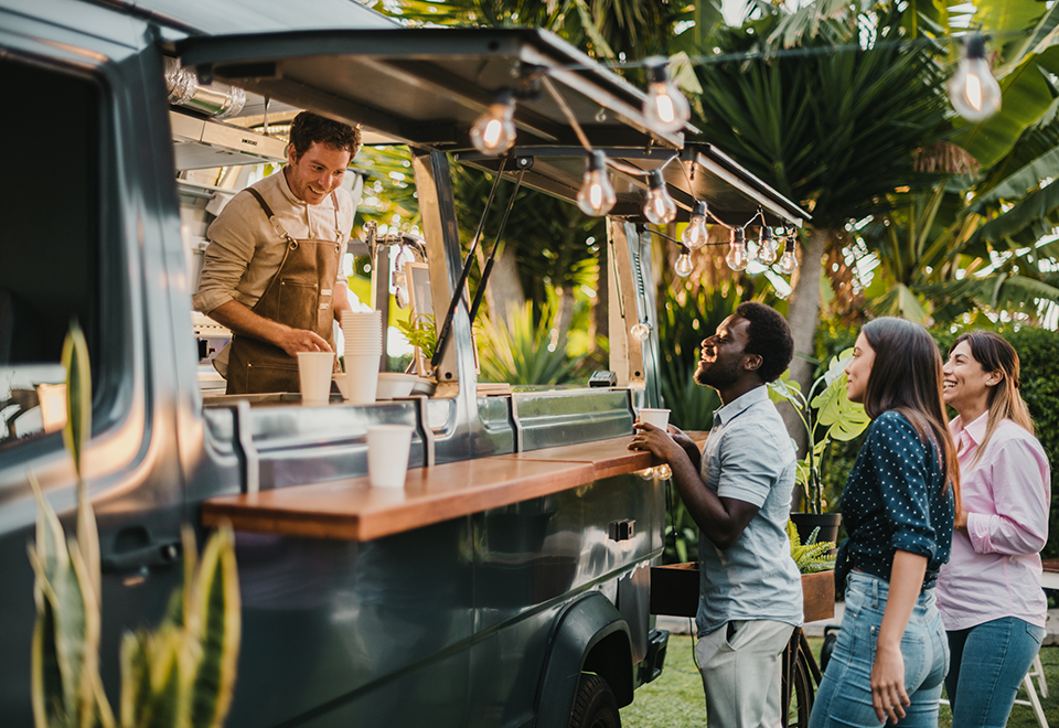 A man is service a group o people from the window of a food truck