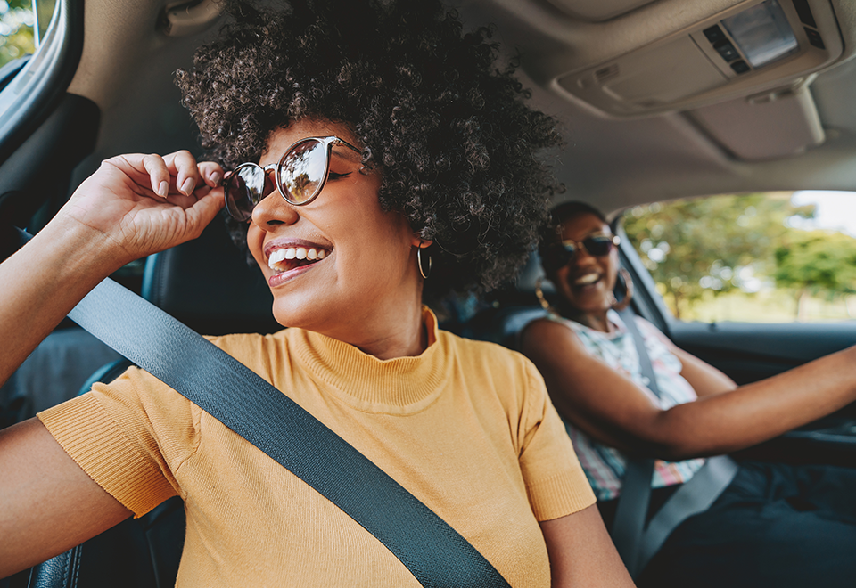 Two friends are in a car smiling