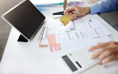 businessman using tablet work on desk holding credit card and checking receipt documents related to business operations calculate expenses paid via credit card before finalizing the account
